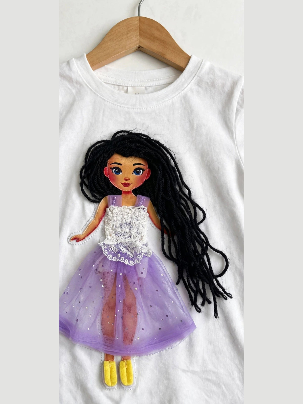 Handmade dark hair doll design in purple tulle skirt on white T-shirt, product photo