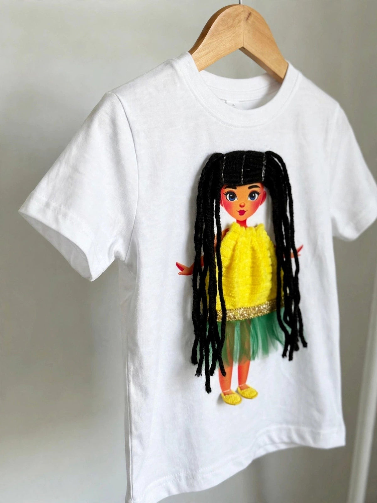 White doll T-shirt with black-haired doll in yellow-green dress, alternate product photo