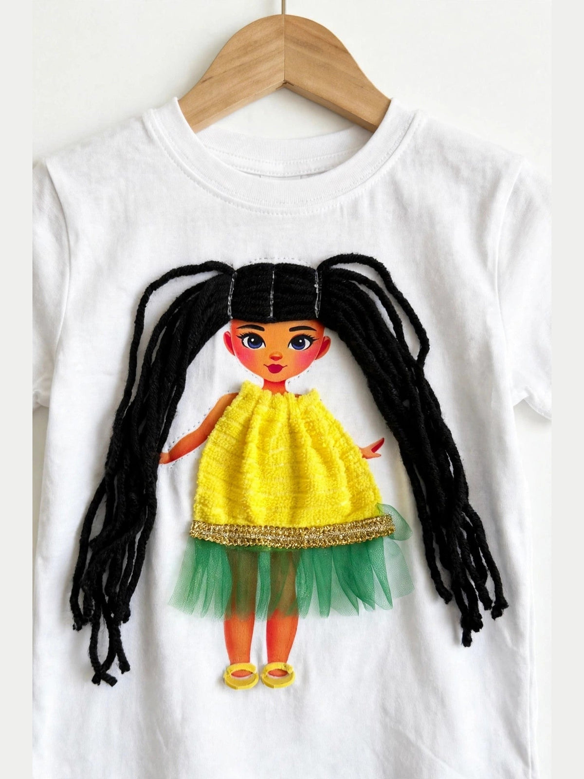 Handmade black hair doll design in yellow-green dress on white T-shirt, product photo
