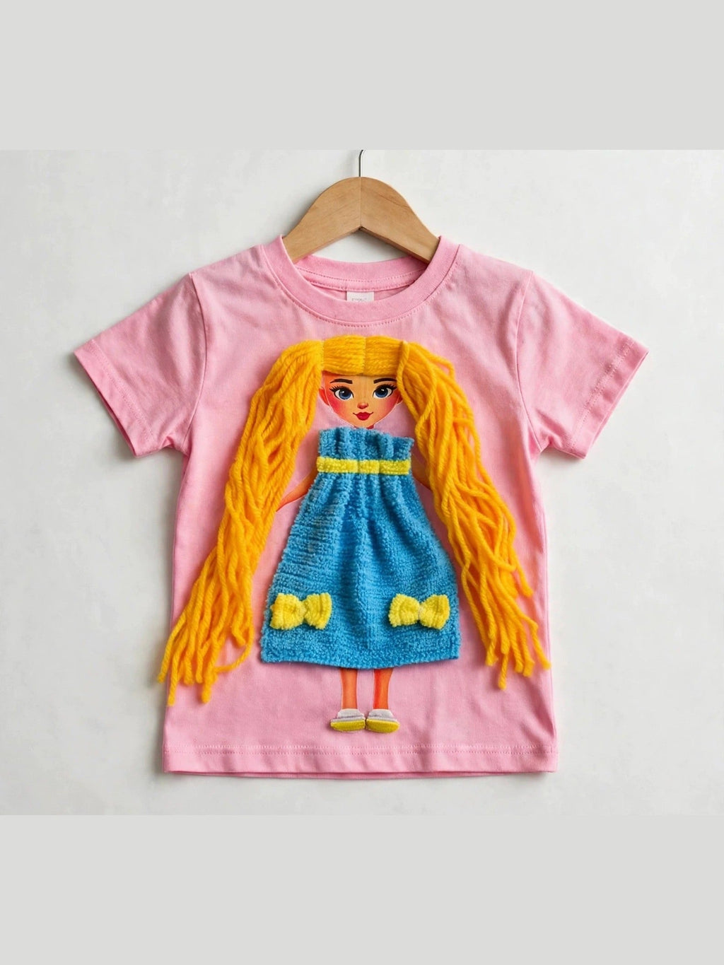 Pink T-shirt with handmade doll appliqué, yellow yarn hair and blue dress