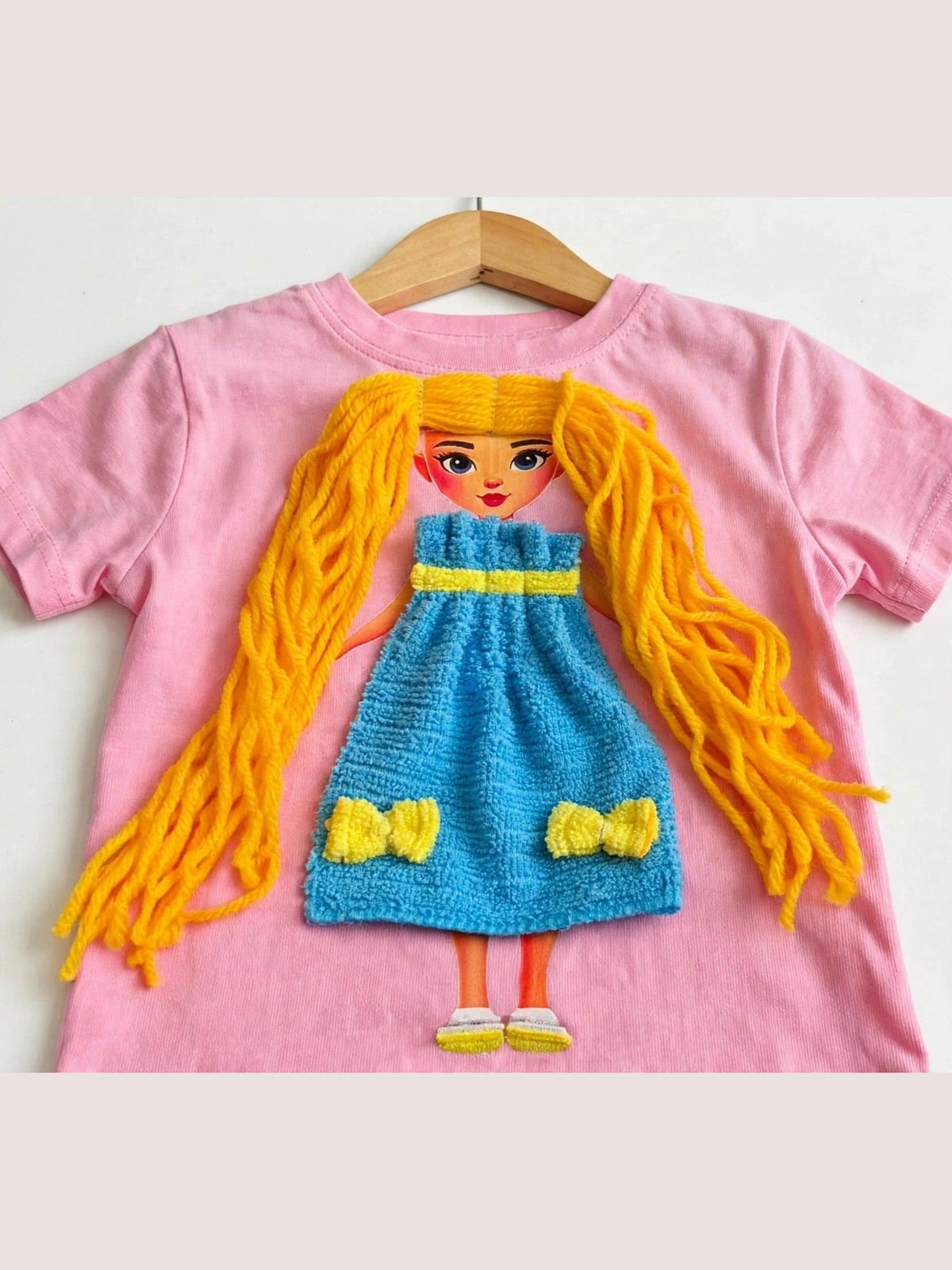 Handmade yellow hair doll design in blue dress on pink T-shirt, product photo
