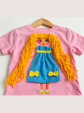 Pink T-shirt with handmade doll appliqué, yellow yarn hair and blue bow dress